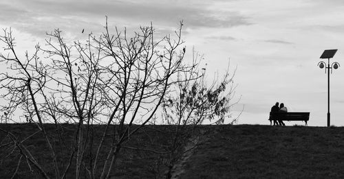 Silhouette bare tree on field against sky