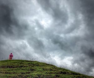 Man on field against storm clouds