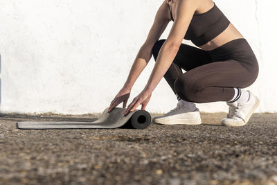 Close up of a woman rolling out a yoga mat outside.