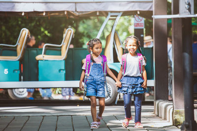 Schoolgirls holding hands while walking on street