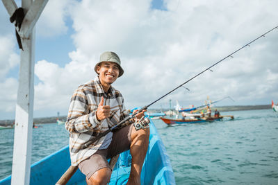 Portrait of young man standing by sea against sky