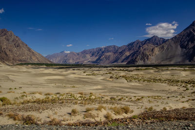 Scenic view of landscape and mountains against blue sky