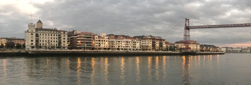 Bridge over river in city against sky