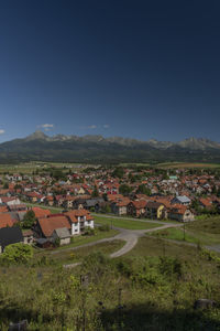 Houses on field by buildings against sky