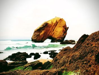 Rock formation on beach against sky