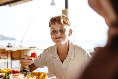 Portrait of boy having watermelon slice for breakfast in resort during vacation