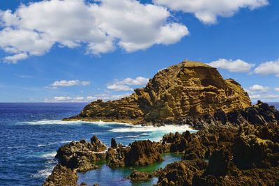 Scenic view of rocks in sea against sky