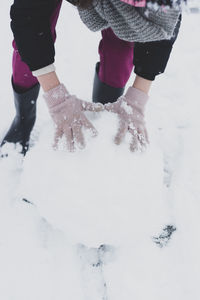 Low section of woman standing on snow covered field