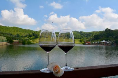 Drinking glass on table by lake against sky