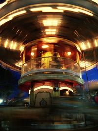 Low angle view of spinning carousel at night