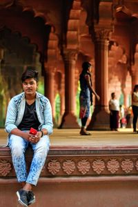 Full length of man sitting at historic building