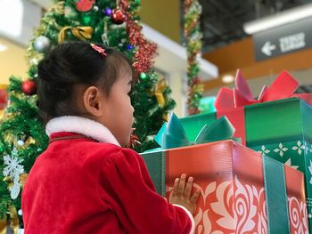 Girl standing against christmas tree and gifts at home