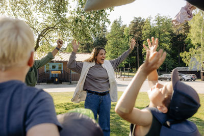 Happy female camp counselor cheering with kids at summer camp