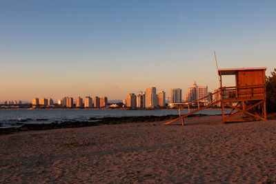 Sea and buildings against clear sky during sunset