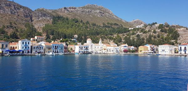 Buildings by sea against blue sky