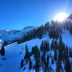 Scenic view of sunset over snow covered mountains against clear blue sky