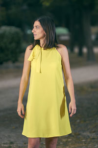 Young woman with yellow umbrella standing outdoors