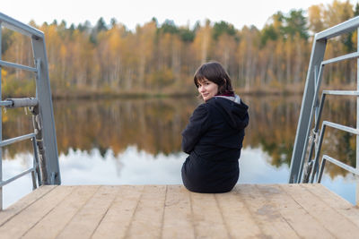 Rear view of woman sitting by lake