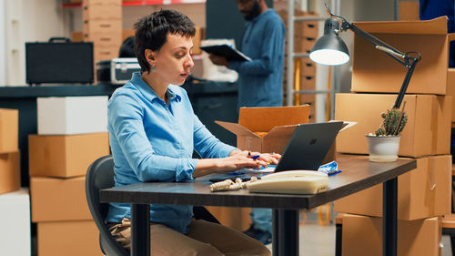 Young woman using laptop while sitting on table