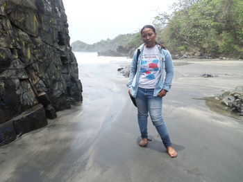 Full length portrait of smiling woman standing on rock