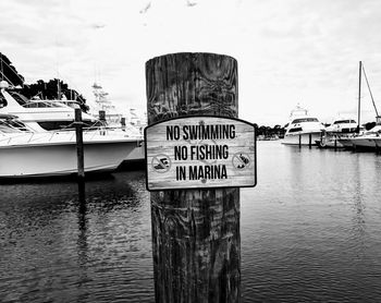 Information sign at harbor against sky