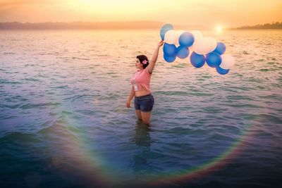 Full length of woman standing at sea against sky during sunset