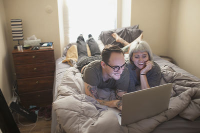 Young couple lying in bed looking at a laptop