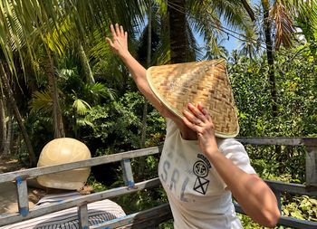 Woman gesturing while wearing asian style conical hat in forest