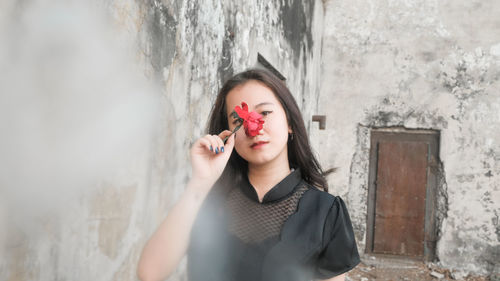 Portrait of a beautiful young woman standing against wall