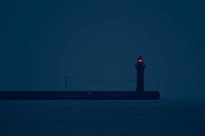 Lighthouse by sea against sky at night