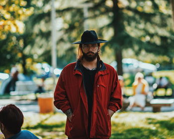 Portrait of young man with hands in pockets wearing hat while standing at park