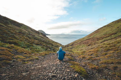 Rear view of man walking on mountain against sky