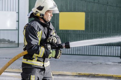 Fire fighter holding water hose outdoors