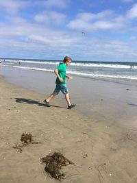 Full length of boy on beach against sky