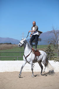 Full length of man standing on horse against sky