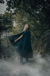 Woman standing by tree in forest