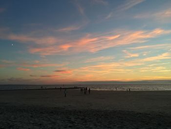 Scenic view of beach against dramatic sky during sunset