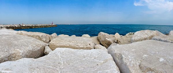 Rocks on beach against blue sky