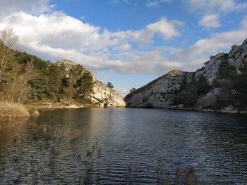 Scenic view of lake by mountains against sky