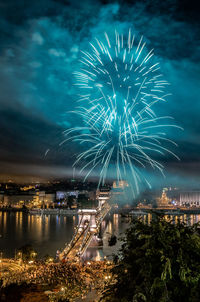 Low angle view of firework display over river at night