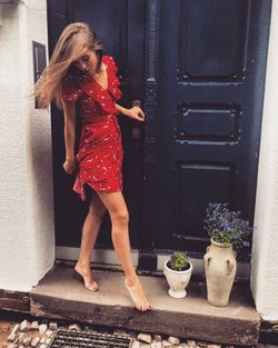 Young woman standing against closed door