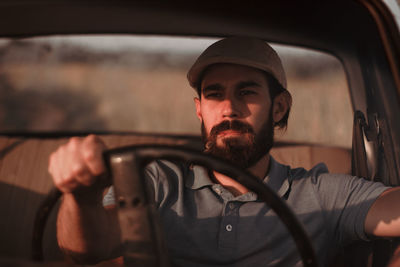 Young man wearing cap sitting in car