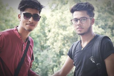 Portrait of male friends standing against trees