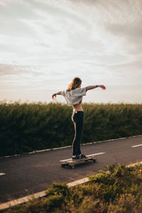 Girl rides a longboard with arms outstretched and enjoying a free ride. sunny day,poster, longboard