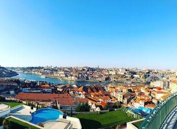 High angle view of houses in town against clear blue sky
