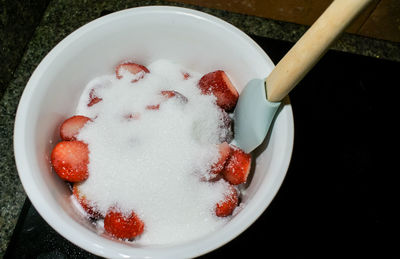 High angle view of strawberries with sugar in bowl on table