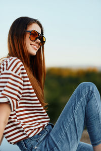 Young woman looking away while sitting on field