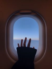 Cropped hand of woman touching airplane window