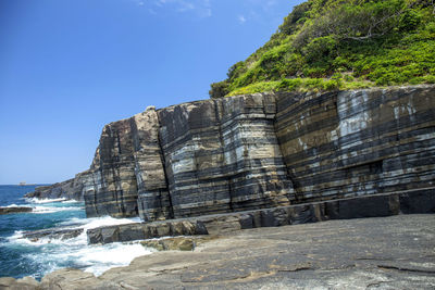 View of rock formation by sea against sky