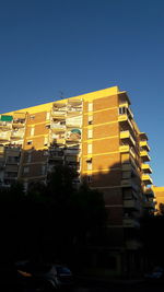 Low angle view of yellow buildings against blue sky